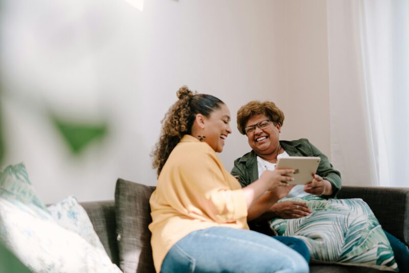 Adult daughter helping her mother with a tablet at home
