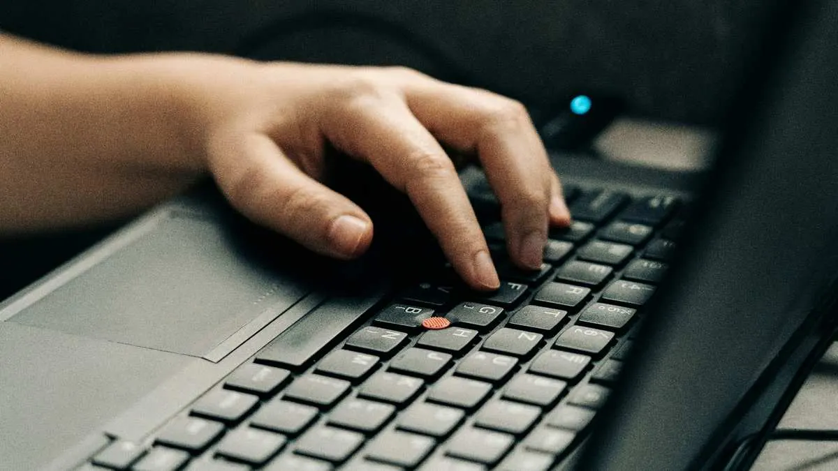 Hands typing on a laptop keyboard managing a small business website and email
